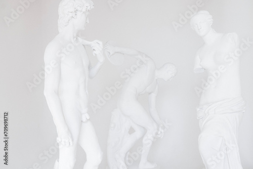 Group of plaster statues on white backdrope. Bonded marble sculptures of Discus thrower  David and Venus.