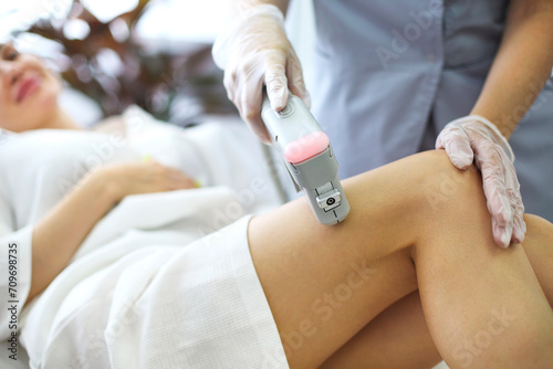 Cropped shot of young fit blonde woman client receiving laser hair removal procedure on body in beauty clinic