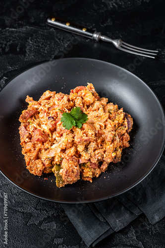 Turkish Menemen, Eggs with tomatoes, green peppers and green onion. Black background. Top view