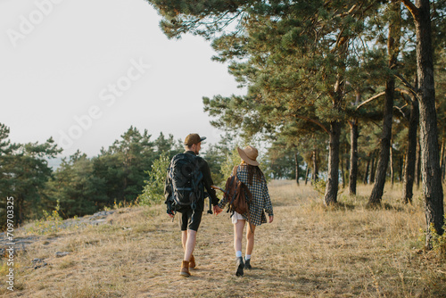 A couple in love holding hands while hiking in the mountains. Rear view.