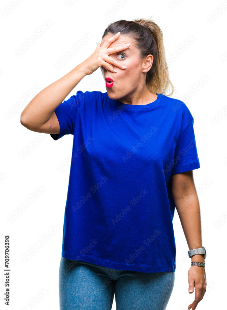Young beautiful woman wearing casual blue t-shirt over isolated background peeking in shock covering face and eyes with hand, looking through fingers with embarrassed expression. Young beautiful woman wearing casual blue t-shirt over isolated background peeking in shock covering face and eyes with hand, looking through fingers with embarrassed expression.