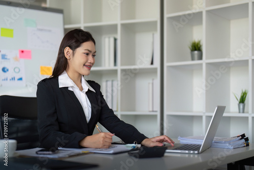 Beautiful asian businesswoman woman using calculator and laptop for doing finance on an office desk, tax, report, accounting, statistics, and analysis research concept