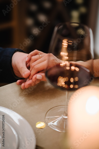 Proposal hand and heart. Hands man and woman hold glasses at home. Toast. Couple in love drinking wine. Cheers. Romantic date by candlelight at night. Dinner setup table for couple on Valentine s day.