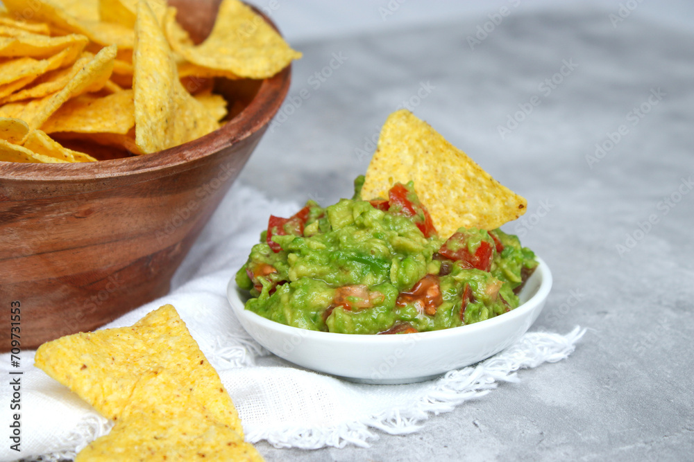 Close up of fresh avocado guacamole dip with salted tortilla chips in wooden bowl Close up of fresh avocado guacamole dip with salted tortilla chips in wooden bowl