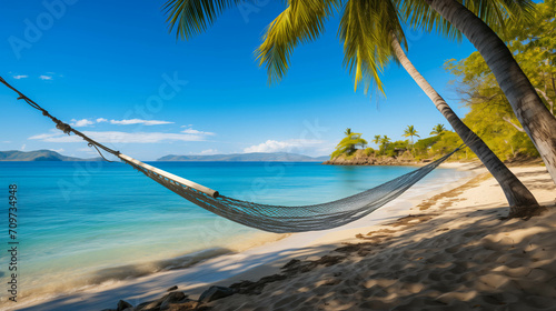 Idyllic tropical beach with a hammock tied between palm trees, overlooking a tranquil blue ocean, suggesting relaxation or summer vacation © AI Petr Images