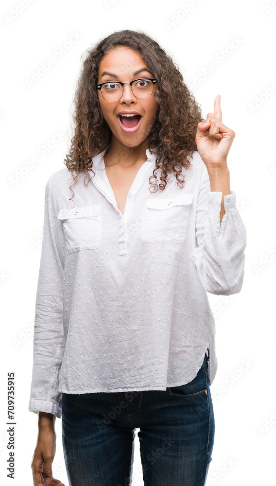 Beautiful young hispanic woman pointing finger up with successful idea. Exited and happy. Number one. Beautiful young hispanic woman pointing finger up with successful idea. Exited and happy. Number one.