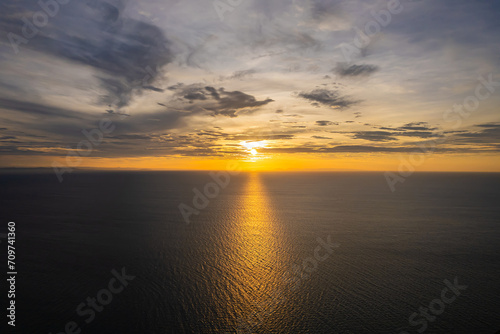 Bright sunrise with yellow sun above the sea surface.