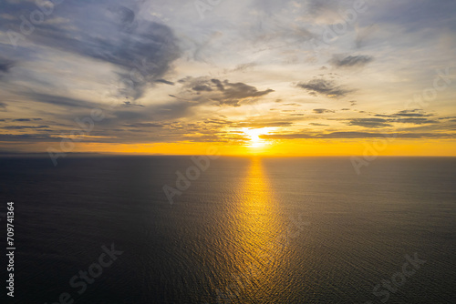 Bright sunrise with yellow sun above the sea surface.