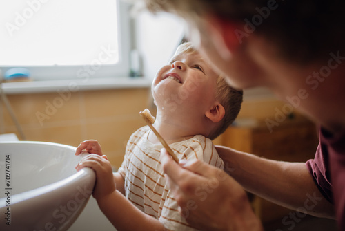 Father brushing little baby boy's teeth in the morning. Morning dental hygiene for toddlers. photo