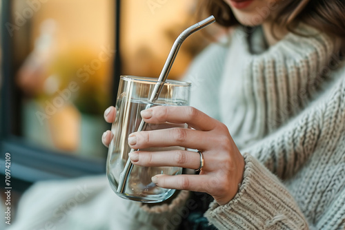 A woman using a reusable stainless steel straw drinking a drink.