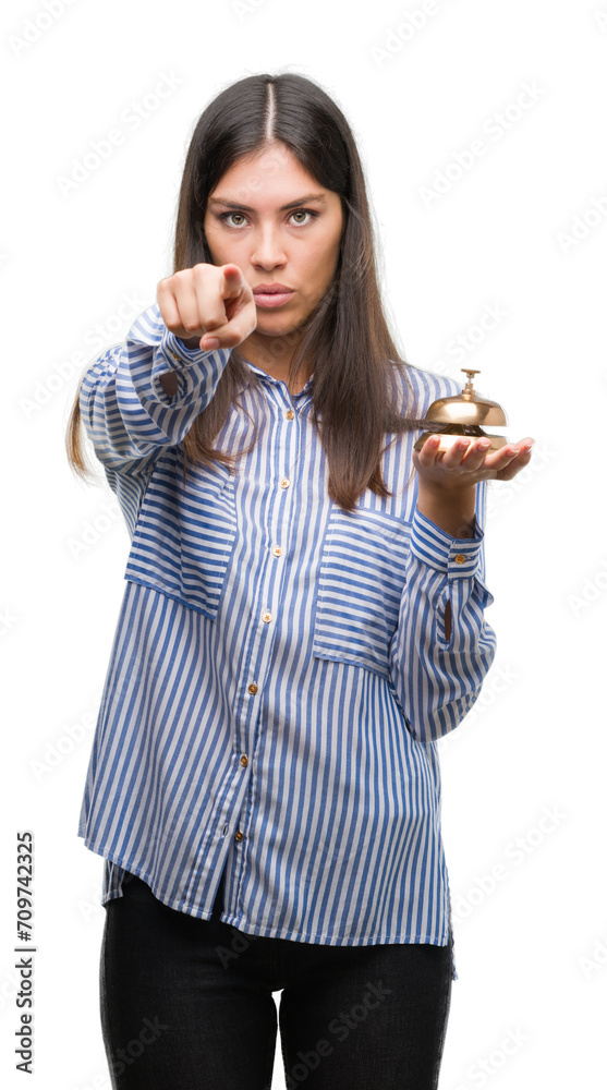 Young beautiful hispanic holding hotel ring bell pointing with finger to the camera and to you, hand sign, positive and confident gesture from the front Young beautiful hispanic holding hotel ring bell pointing with finger to the camera and to you, hand sign, positive and confident gesture from the front