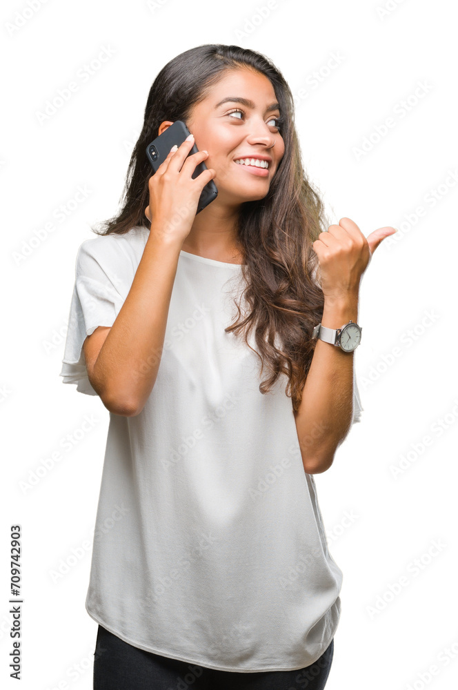 Young beautiful arab woman talking on the phone over isolated background pointing and showing with thumb up to the side with happy face smiling