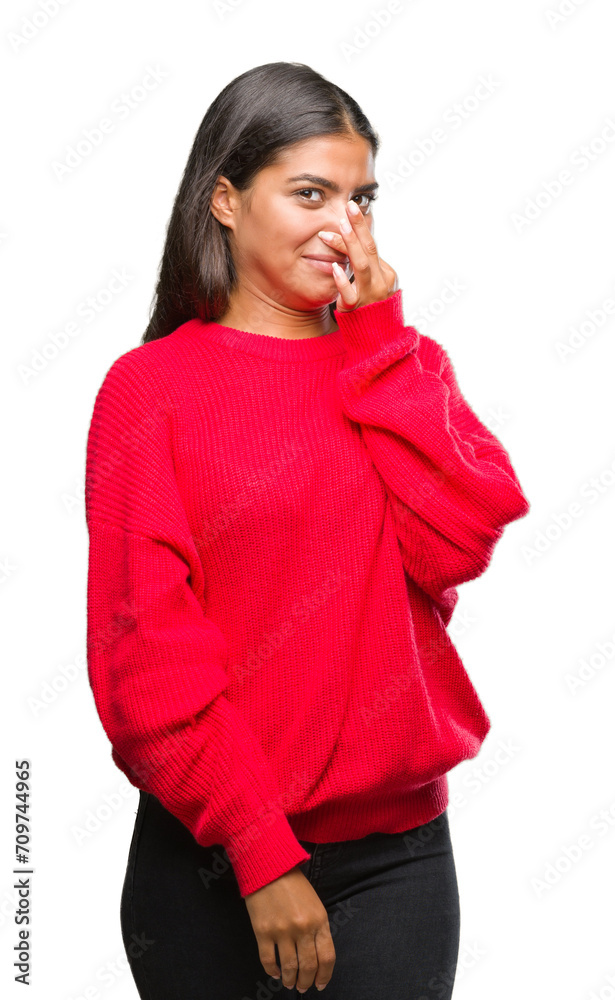 Young beautiful arab woman wearing winter sweater over isolated background smelling something stinky and disgusting, intolerable smell, holding breath with fingers on nose. Bad smells concept. Young beautiful arab woman wearing winter sweater over isolated background smelling something stinky and disgusting, intolerable smell, holding breath with fingers on nose. Bad smells concept.