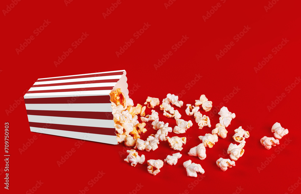 Obraz premium box with popcorn striped in different colors on a red background