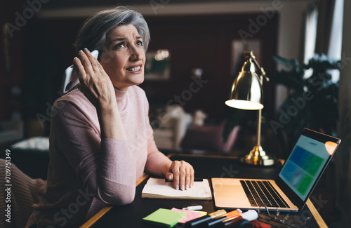 Confused mature freelancer with smartphone and laptop