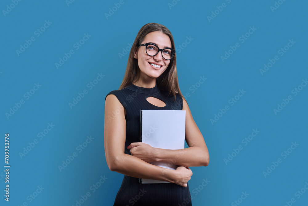 Young business woman with clipboard looking at camera on blue background Young business woman with clipboard looking at camera on blue background