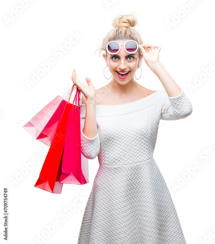 Young beautiful blonde woman holding shopping bags over isolated background scared in shock with a surprise face, afraid and excited with fear expression