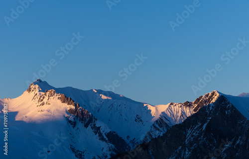 vue panoramique sur les sommets enneigés éclairés par les derniers rayons du soleil couchant