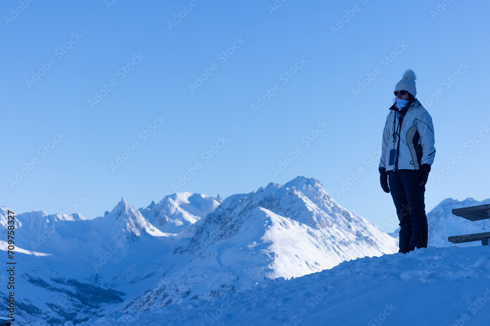 vue panoramique d'une femme qui admire le paysage de montagne hivernal debout sur un sommet enneigé.