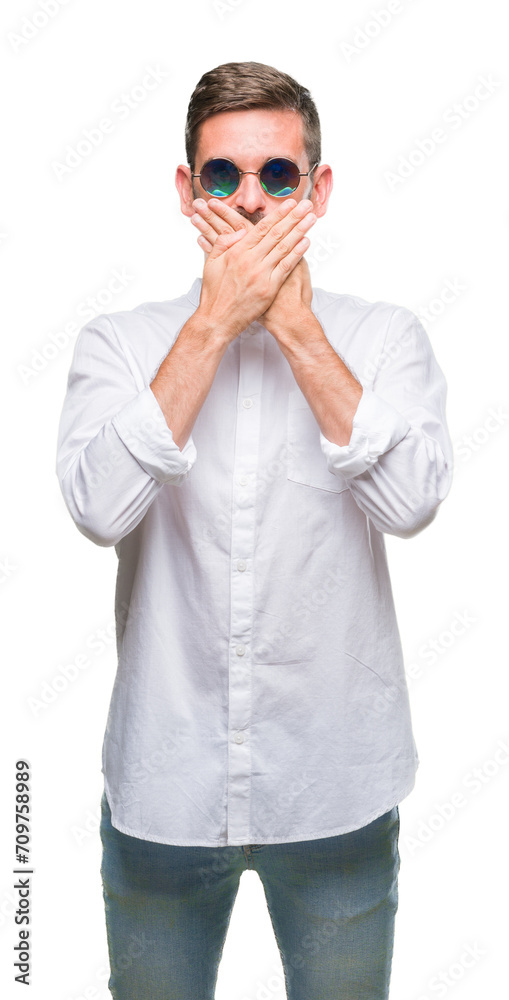 Young handsome man wearing glasses over isolated background shocked covering mouth with hands for mistake. Secret concept. Young handsome man wearing glasses over isolated background shocked covering mouth with hands for mistake. Secret concept.
