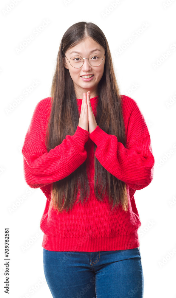 Young Chinese woman over isolated background wearing glasses praying with hands together asking for forgiveness smiling confident.