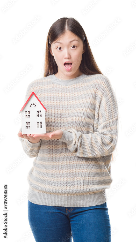 Young Chinese real state agent woman over isolated background holding house scared in shock with a surprise face, afraid and excited with fear expression Young Chinese real state agent woman over isolated background holding house scared in shock with a surprise face, afraid and excited with fear expression