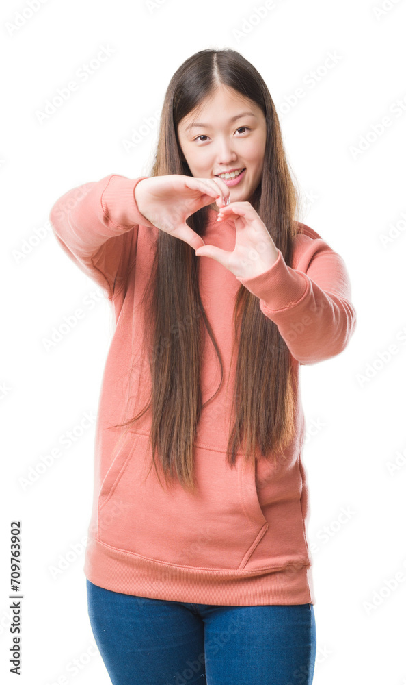 Young Chinese woman over isolated background wearing sport sweathshirt smiling in love showing heart symbol and shape with hands. Romantic concept. Young Chinese woman over isolated background wearing sport sweathshirt smiling in love showing heart symbol and shape with hands. Romantic concept.