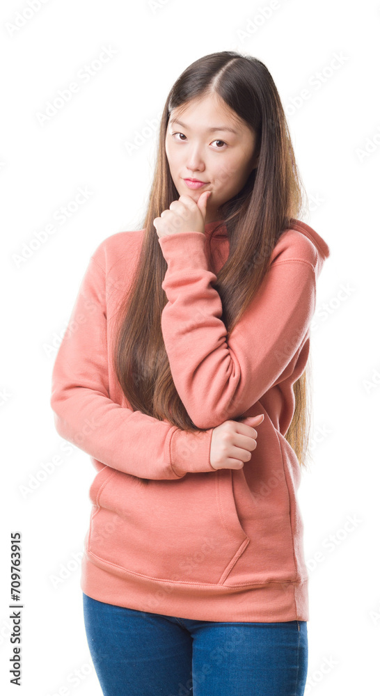 Young Chinese woman over isolated background wearing sport sweathshirt looking confident at the camera with smile with crossed arms and hand raised on chin. Thinking positive.