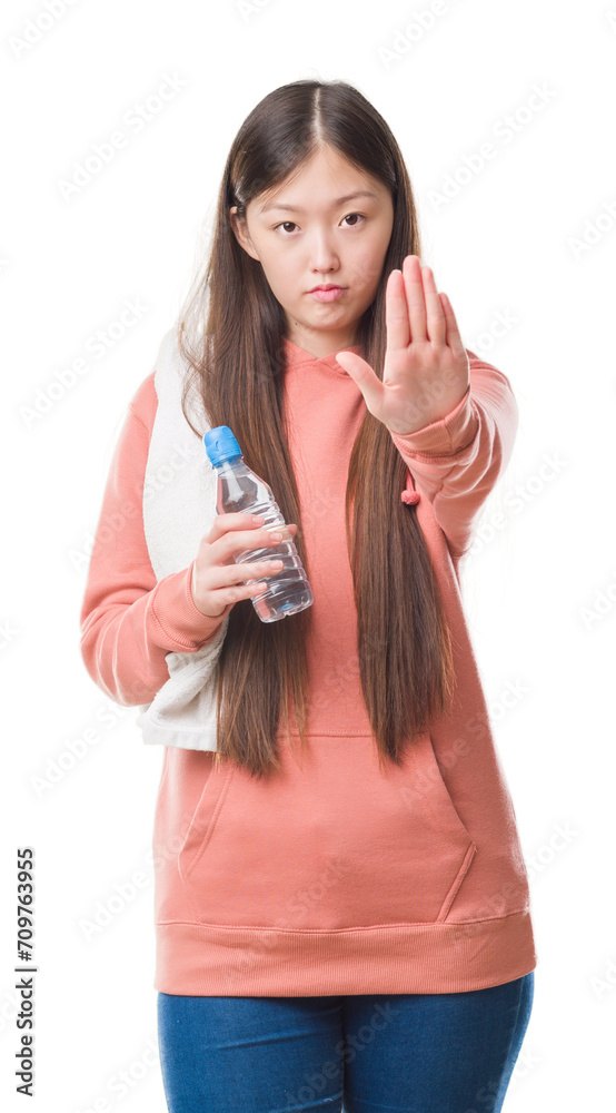 Young Chinese woman over isolated background wearing sport sweathshirt with open hand doing stop sign with serious and confident expression, defense gesture Young Chinese woman over isolated background wearing sport sweathshirt with open hand doing stop sign with serious and confident expression, defense gesture