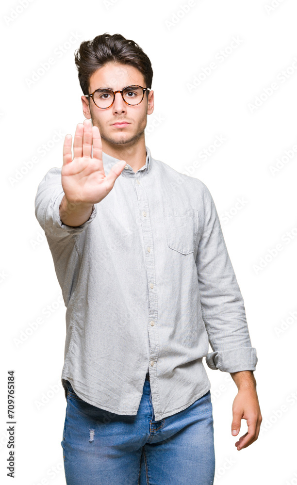 Young handsome man wearing glasses over isolated background doing stop sing with palm of the hand. Warning expression with negative and serious gesture on the face.