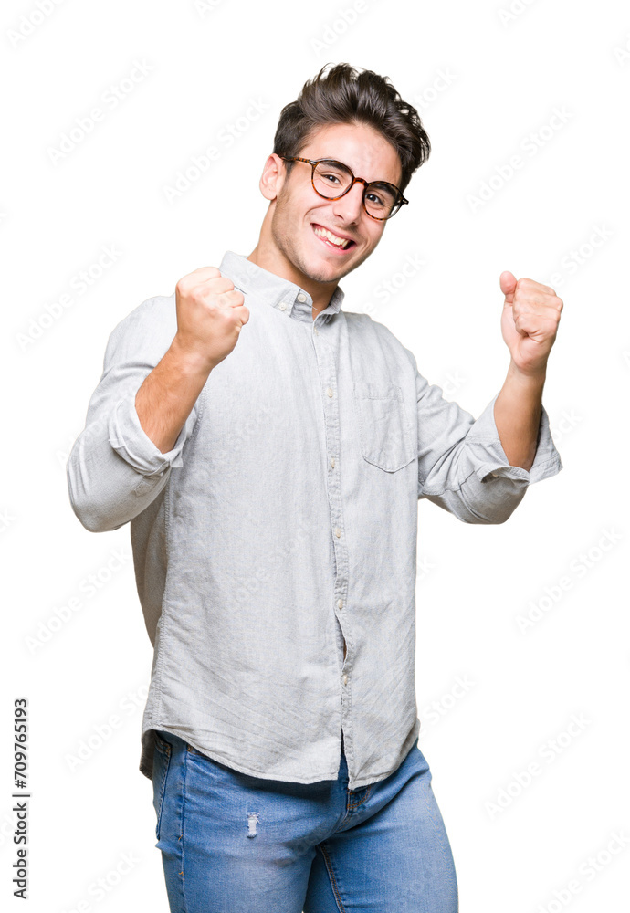 Fototapeta premium Young handsome man wearing glasses over isolated background very happy and excited doing winner gesture with arms raised, smiling and screaming for success. Celebration concept.
