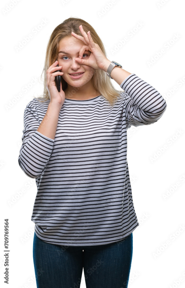 Young caucasian woman showing smartphone screen over isolated background with happy face smiling doing ok sign with hand on eye looking through fingers Young caucasian woman showing smartphone screen over isolated background with happy face smiling doing ok sign with hand on eye looking through fingers