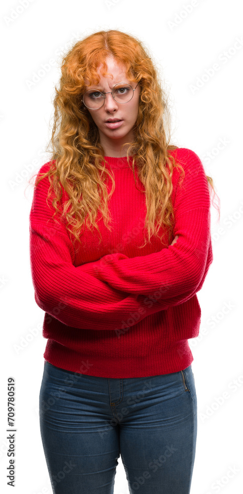Young redhead woman wearing red sweater skeptic and nervous, disapproving expression on face with crossed arms. Negative person. Young redhead woman wearing red sweater skeptic and nervous, disapproving expression on face with crossed arms. Negative person.