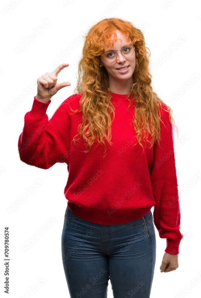 Young redhead woman wearing red sweater smiling and confident gesturing with hand doing size sign with fingers while looking and the camera. Measure concept. Young redhead woman wearing red sweater smiling and confident gesturing with hand doing size sign with fingers while looking and the camera. Measure concept.