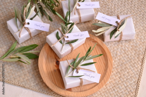 Wedding favors white boxes guest gifts soaps decoration jute ribbon and green olive leaves, mediterranean rustic style ceremony, jewelry box, small gift, wood plate background natural colors