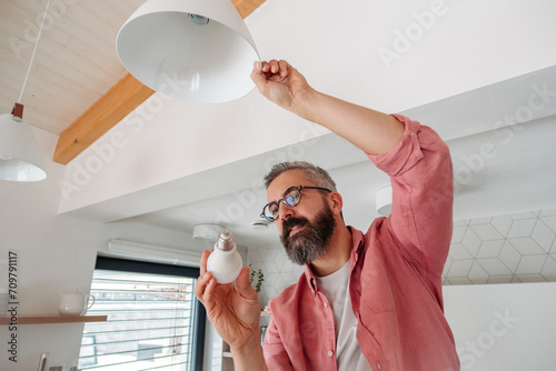 Man changing LED bulbs at home. Concept of energy efficiency, longevitiy and environmental impact of electronic bulb. photo