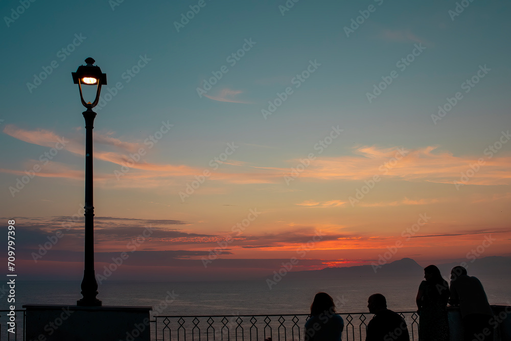 A lantern and unrecognizable silhouettes of people against the backdrop of a fantastic sunset A lantern and unrecognizable silhouettes of people against the backdrop of a fantastic sunset