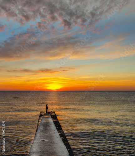 Fototapeta Naklejka Na Ścianę i Meble -  The pier goes out to sea at sunrise. Dawn over the sea.