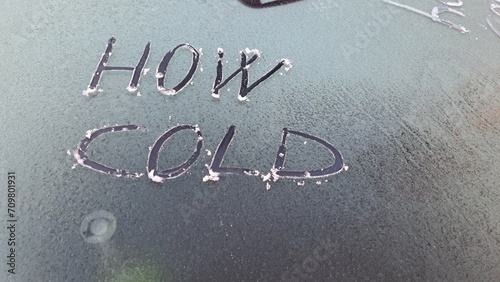 Che freddo scritto su un'auto con il parabrezza coperto di ghiaccio.