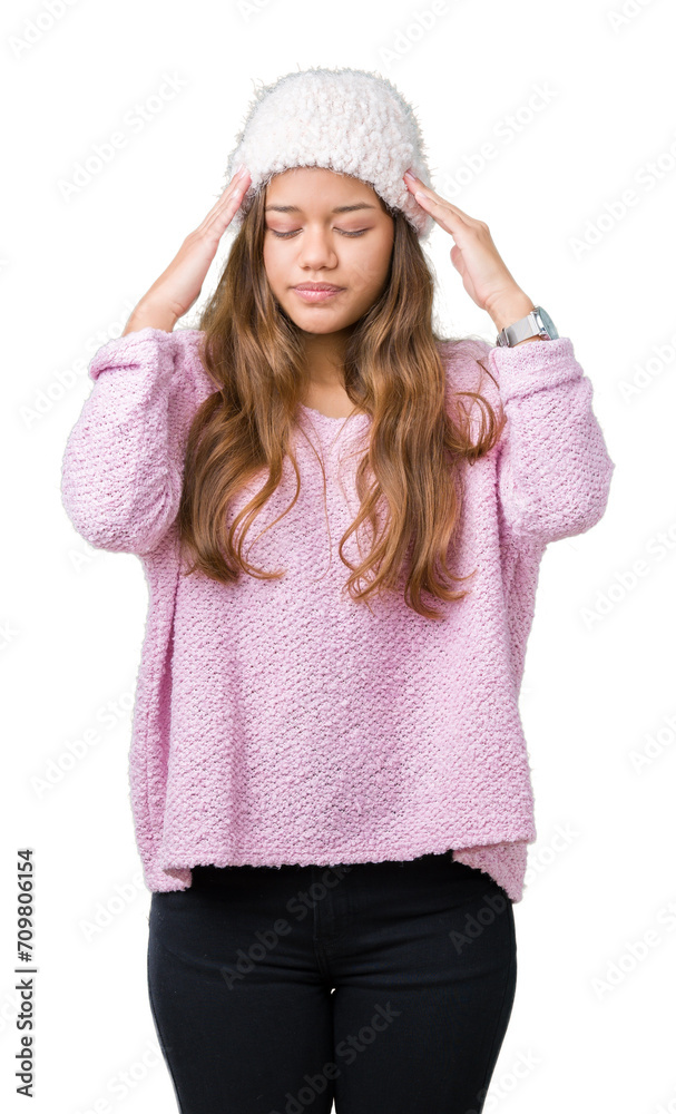 Young beautiful brunette woman wearing sweater and winter hat over isolated background with hand on head for pain in head because stress. Suffering migraine.