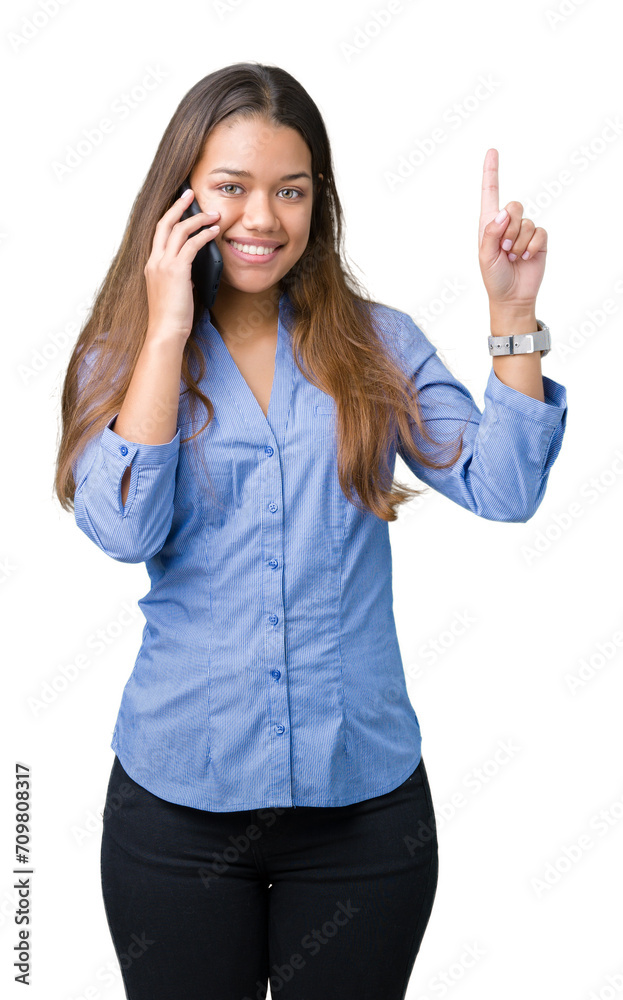 Young beautiful brunette business woman talking on smartphone over isolated background surprised with an idea or question pointing finger with happy face, number one