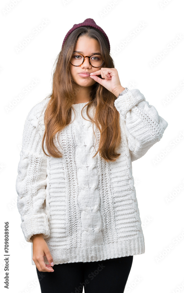 Young beautiful brunette hipster woman wearing glasses and winter hat over isolated background mouth and lips shut as zip with fingers. Secret and silent, taboo talking Young beautiful brunette hipster woman wearing glasses and winter hat over isolated background mouth and lips shut as zip with fingers. Secret and silent, taboo talking