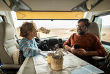 Couple enjoys the weekend aboard their camper. Happy man together with his wife spending pleasant moments. Concept of freedom and free time