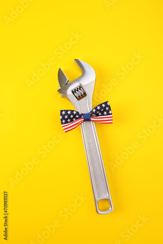 Labor day. A wrench with a bow tie on a yellow background.A bright background for the design of the postcard. The concept of a national holiday.Father's Day.Plumber's Day.Vertical photo