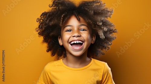 Laughing black boy isolated on orange background. Cheerful black kid in orange t-shirt.