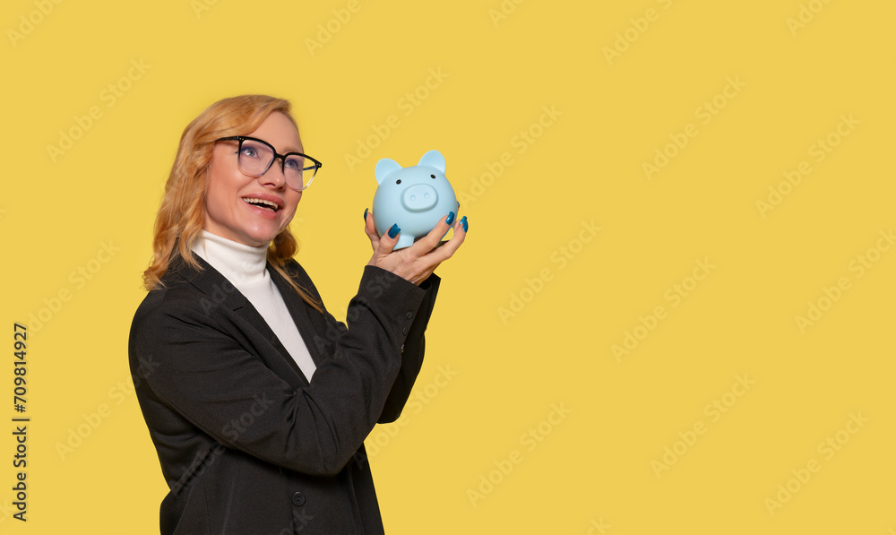 Happy woman in smart black jacket discovering piggy bank without savings. Investment, saving money, currency, deposit. Indoor studio shot isolated on yellow background. Happy woman in smart black jacket discovering piggy bank without savings. Investment, saving money, currency, deposit. Indoor studio shot isolated on yellow background.