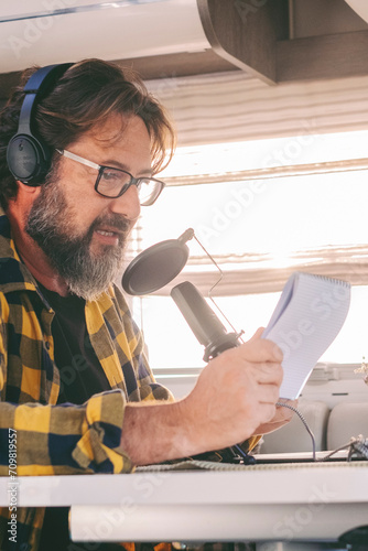 Modern online work in alternative office lifestyle. Traveler use online connection for his job. Man recording and speaking at the microphone and laptop computer. Creator content people living in van