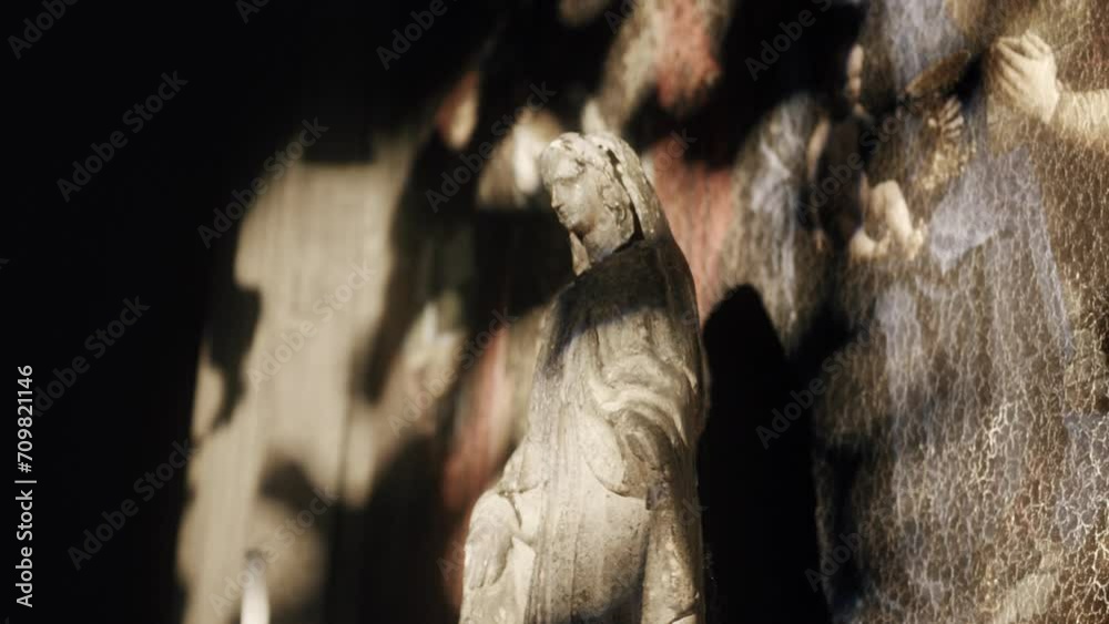 Antique old statue on the background of a stone fresco wall. Impressive Gothic sculpture in the church. Close-up, depth of field, 4K