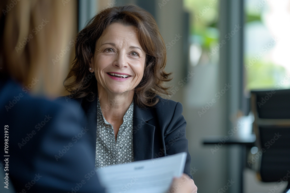 Confident Mature Businesswoman in Corporate Setting Engaging in Professional Consultation, Holding CV with a Pleasant Demeanor, Legal Advisor at Work, Employment Expert Discussing Career Opportunities Confident Mature Businesswoman in Corporate Setting Engaging in Professional Consultation, Holding CV with a Pleasant Demeanor, Legal Advisor at Work, Employment Expert Discussing Career Opportunities