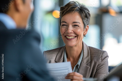 Confident Mature Businesswoman in Corporate Setting Engaging in Professional Consultation, Holding CV with a Pleasant Demeanor, Legal Advisor at Work, Employment Expert Discussing Career Opportunities